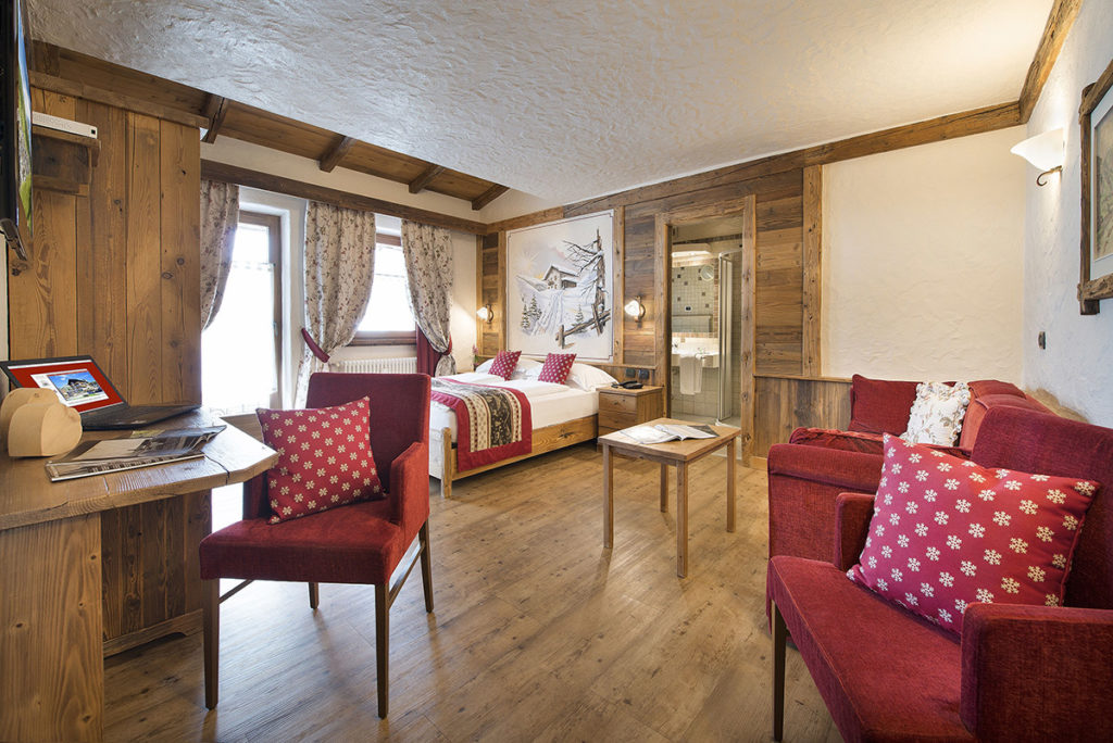 Junior Suite con poltrone rosse e pareti in legno